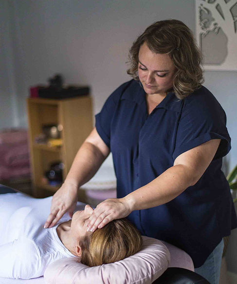 Adeline Savary, kinésiologue, effectuant une séance de kinésiologie sur une cliente allongée.